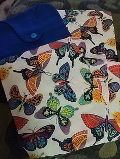 a bag with butterflies on it sitting on the floor next to a blanket and pillow