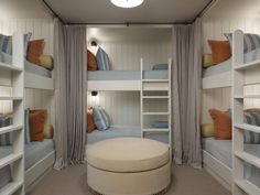 a room with bunk beds and pillows on top of the bed, along with a round ottoman