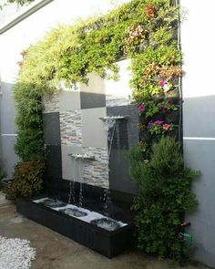 an outdoor fountain with plants growing on it's sides and water running down the side