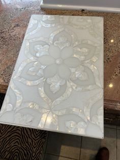 a marble table with an intricate design on it's top and the bottom part of the table is white