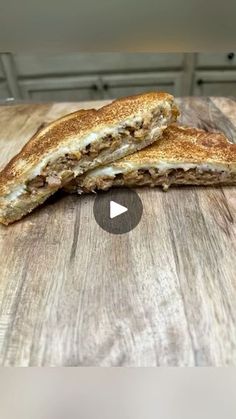 two pieces of toasted sandwich sitting on top of a wooden cutting board next to a knife