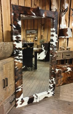 a cowhide mirror is on display in a room with wooden walls and flooring