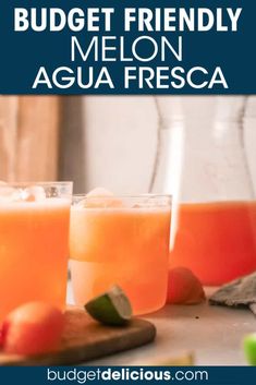 two glasses filled with orange juice on top of a wooden cutting board next to fruit