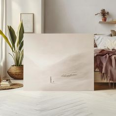 a bed with a blanket on top of it next to a plant in a vase