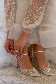 a close up of a person wearing high heels and holding something in their hand while sitting on the ground