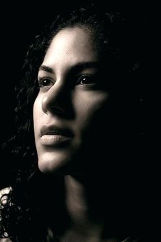 a black and white photo of a woman with curly hair looking off to the side