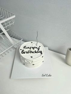 a birthday cake sitting on top of a table next to a cup and wire rack