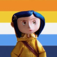 a doll with blue hair wearing a yellow jacket and carrying a brown bag in front of a rainbow striped background