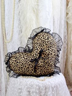 a leopard print heart shaped pillow sitting on top of a white tablecloth covered table