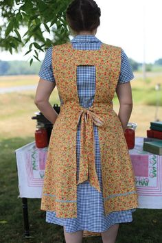 a woman standing in front of a table with food on it and wearing an apron