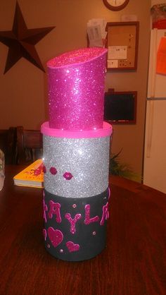 three tiered cake decorated with pink and silver glitters on top of a wooden table