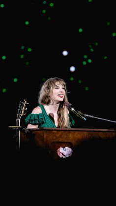 a woman standing at a podium in front of a microphone and green lights behind her