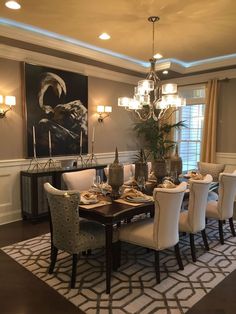 a dining room table with white chairs and a chandelier