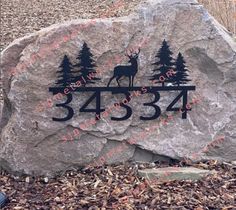 a large rock with a deer and trees on it in front of a forest area