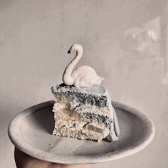 a piece of cake with a white swan on top is being held by a hand