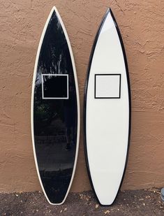 two surfboards sitting next to each other near a wall