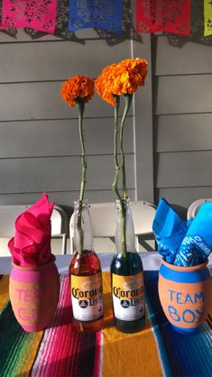 three vases with flowers in them sitting on a colorful table cloth next to each other