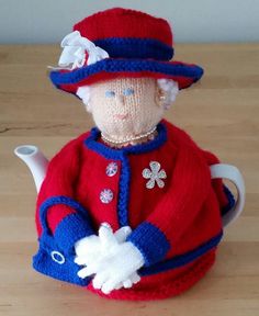 a knitted doll in a red jacket and hat with a teapot on the table