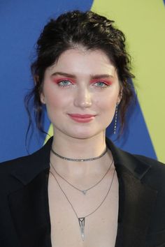 a close up of a person wearing a black suit and red eyeliners on her face