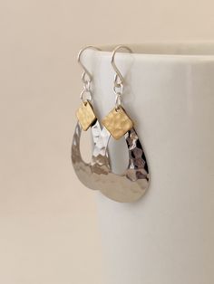 These teardrop shaped dangle earrings are lightweight and fun to wear.  Designed with a silver-plated hammered brass teardrop and topped with a hammered brass accent.   Sterling silver ear wire Mixed metal earrings for every day. Includes cloth storage pouch, gift box, and cloth ribbon.  Our brass jewelry is nickel-free, lead-free and cadmium-free. Earring Drop: 2.5 inches or approx. 60mm Dimensions: Silver teardrop measures 0.75 inches across Minimalism simple style Casual earrings Everyday ear Hammered Metal Jewelry Clasps, Everyday Earrings Silver, Hammered Metal Jewelry, Cloth Storage, Hammered Jewelry, Mixed Metal Earrings, Casual Earrings, Earrings Everyday, Mixed Metal Jewelry