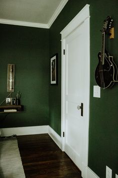 a guitar hangs on the wall next to a door in a room with green walls