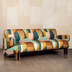 a multicolored couch sitting in front of a wall