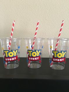 three toy story cups with straws in them on a table next to a wall