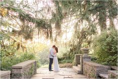 a bride and groom standing on a stone bridge in the woods at their wedding day