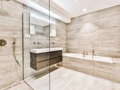 a bathroom with a glass shower door, sink and bathtub in the middle of it