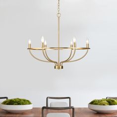 a chandelier hanging over a dining room table with two white bowls on it