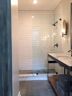 a bathroom with a walk in shower next to a white tiled wall and counter top