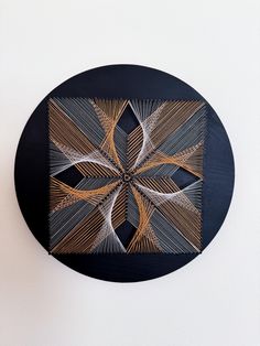 a black and white wall clock with an intricate design on it's face, against a white wall