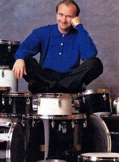 a man sitting on top of a pile of drum sets with his hands in his ears