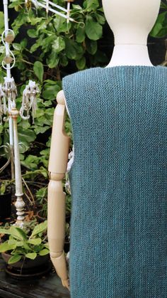 a mannequin wearing a blue sweater in front of some plants