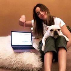 a woman sitting on the floor with her dog and laptop computer in front of her