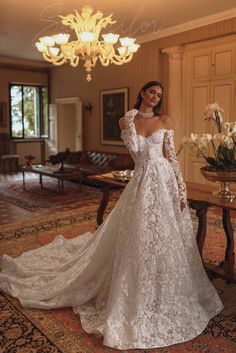 a woman in a white wedding dress standing on a rug near a chandelier