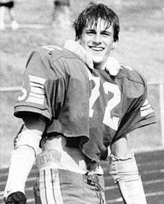 an old photo of a football player on the field smiling for the camera with his hands in his pockets