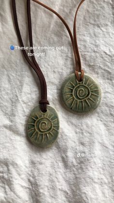 two necklaces that are sitting on top of a white cloth covered surface, one has an evil eye and the other has a brown leather cord