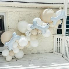 a dog bone and bone balloon arch on the front porch of a house with balloons attached to it