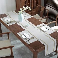 a dining room table with place settings and flowers in a vase on the table top