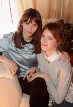 two women sitting on a couch posing for the camera