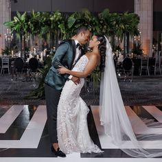 a bride and groom kissing on the dance floor in front of an elegant reception table