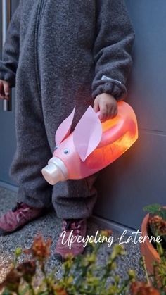 a young child standing next to a wall with a light up pig shaped object in it's mouth