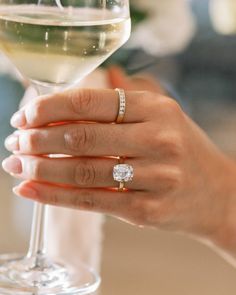 a close up of a person holding a wine glass with a diamond ring on it