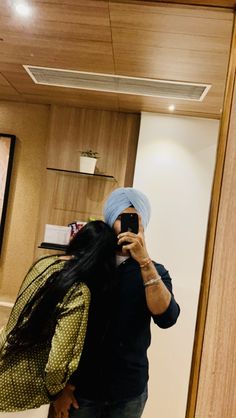 a man taking a selfie in front of a mirror wearing a turban