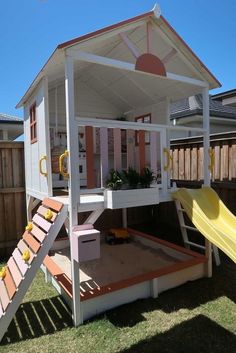 a play house with a slide in the back and a yellow slide on the front