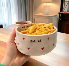 someone holding up a bowl full of chips with the words eat me written on it