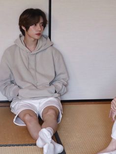 two people sitting on the floor with their legs crossed and one person wearing white socks