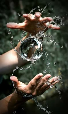 two hands are holding water in the air