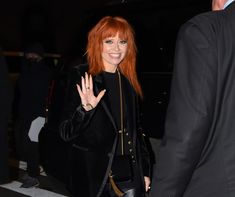 a woman with red hair waves to the crowd